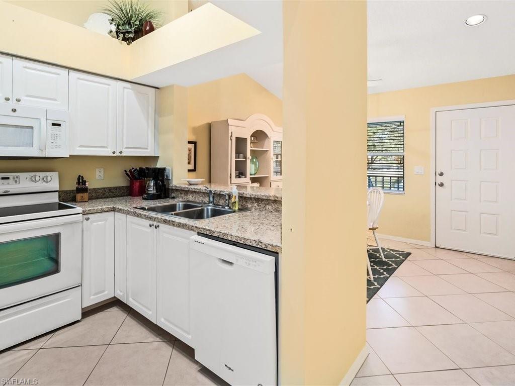 149 Wading Bird Circle, Unit I205 Naples, FL 34110 - Photo 6 of 27 a kitchen with stainless steel appliances granite countertop a sink and cabinets