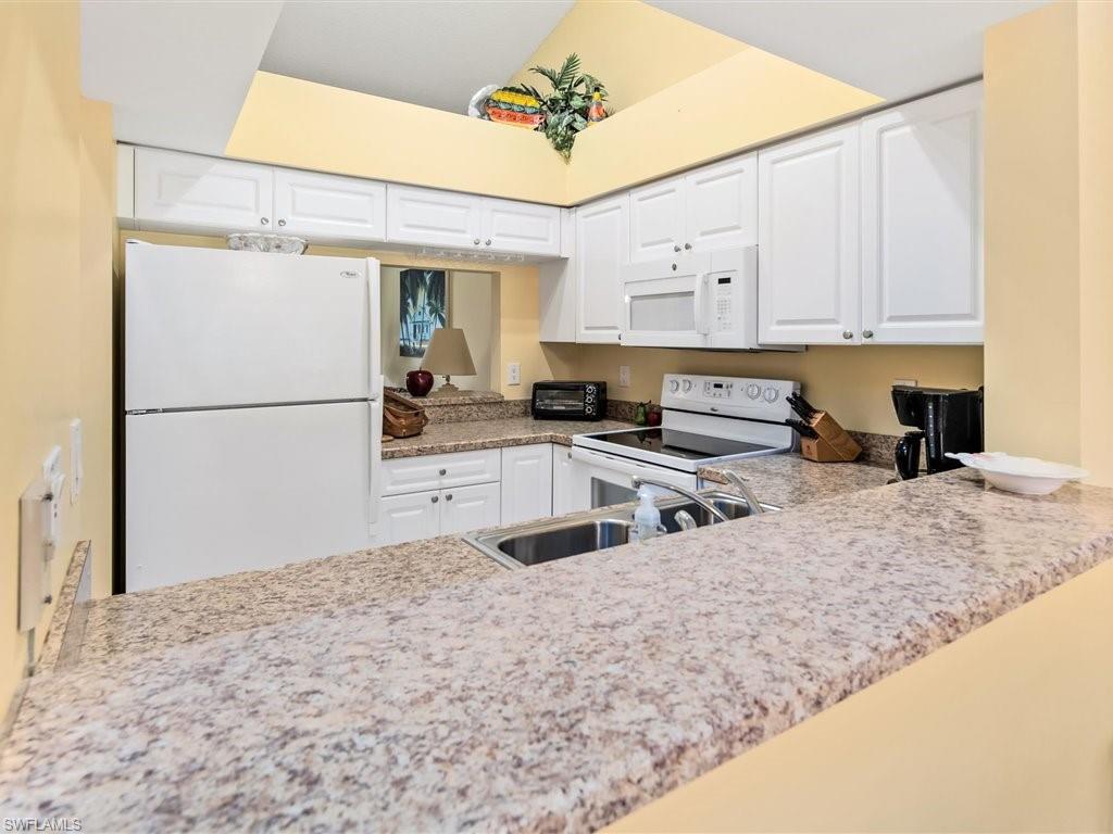 149 Wading Bird Circle, Unit I205 Naples, FL 34110 - Photo 7 of 27 a kitchen with granite countertop a sink stainless steel appliances and cabinets