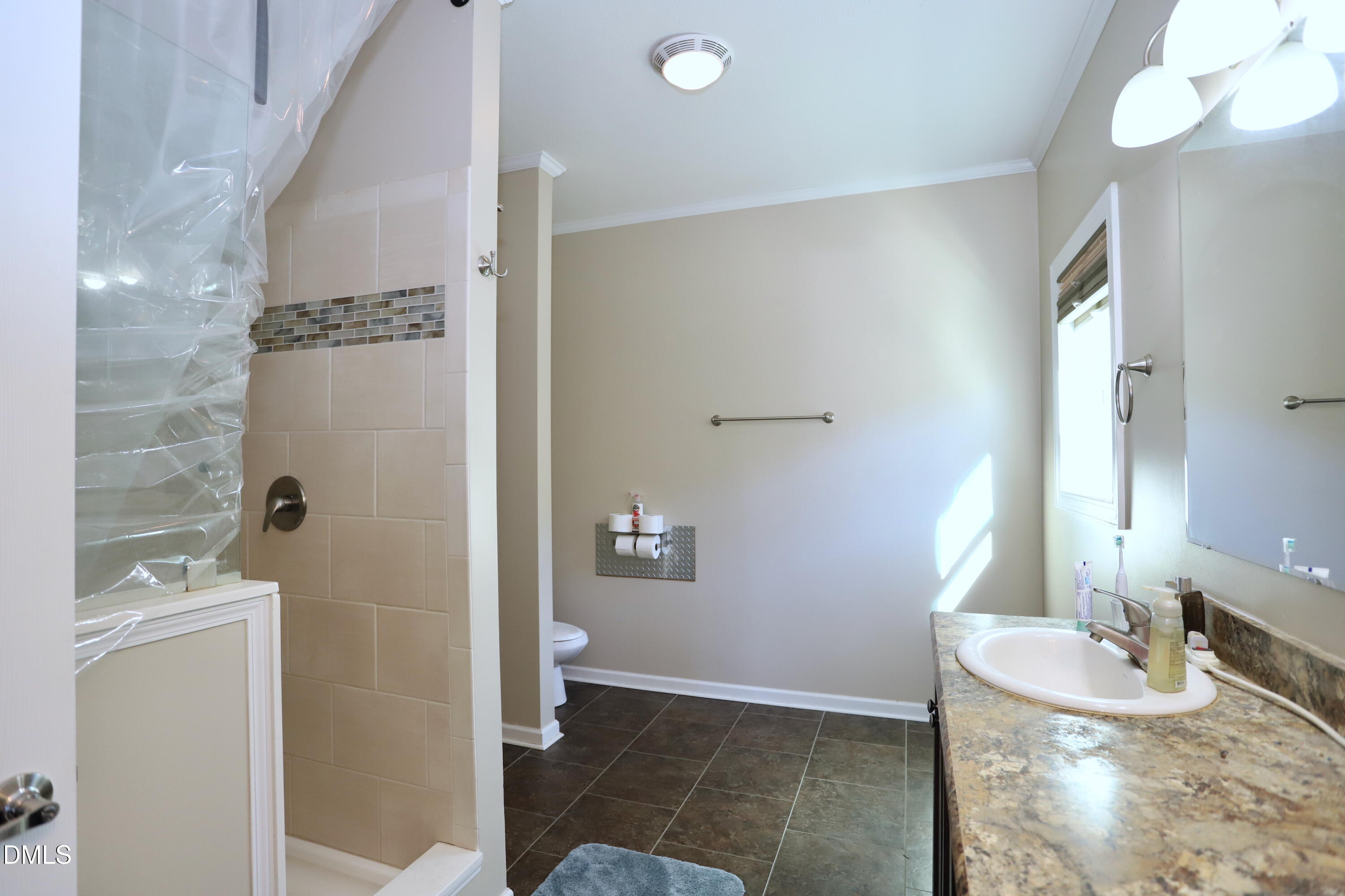 6764 Bradshaw Farm Road Efland, NC 27243 - Photo 16 of 56 a bathroom with a granite countertop sink a toilet a mirror and shower