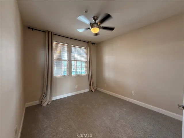 an empty room with ceiling fan and windows