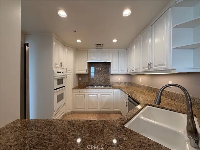 a kitchen with granite countertop white cabinets and stainless steel appliances