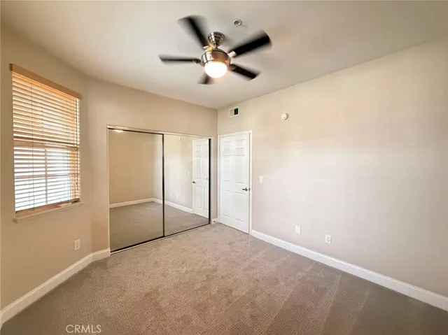 a view of an empty room with a ceiling fan and window