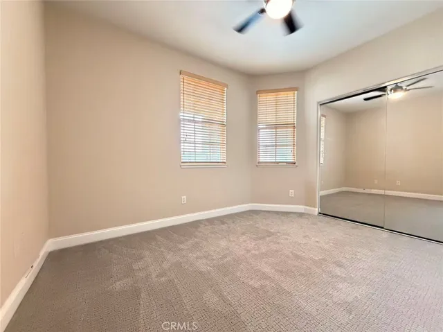 an empty room with ceiling fan and windows