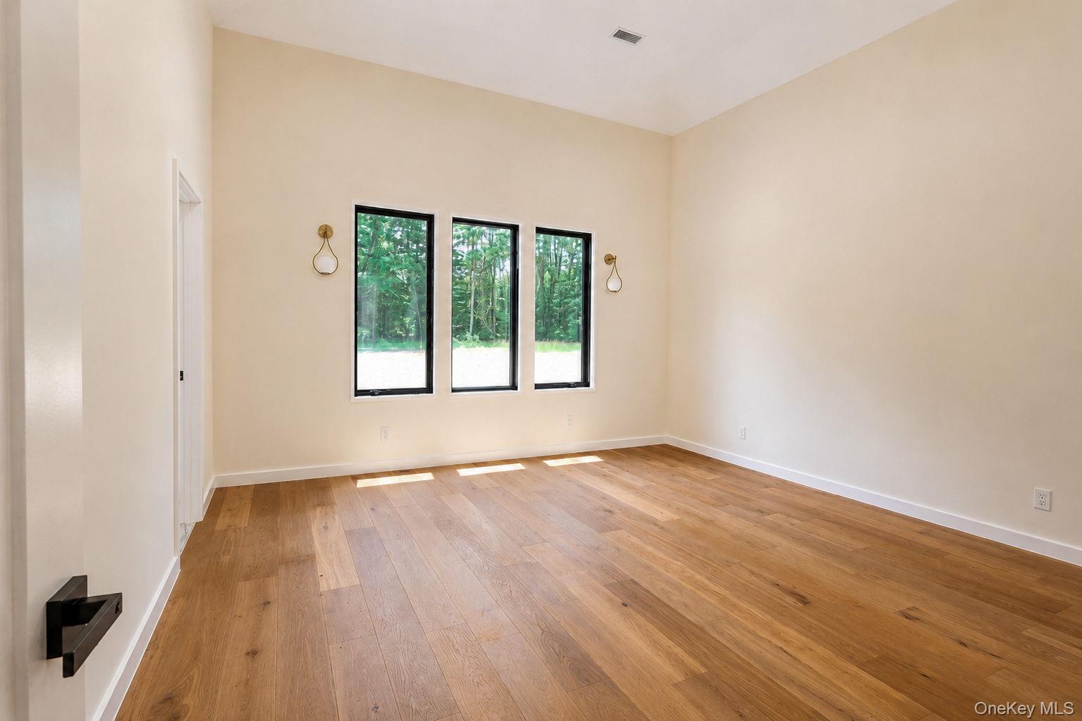 128 St Elmo Road Wallkill, NY 12589 - Photo 23 of 45 Spacious room featuring light-toned walls, wood-finish flooring, and three vertical windows with black frames
