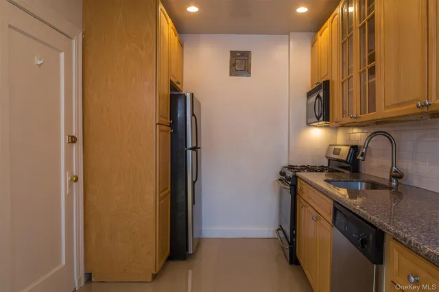 a kitchen with stainless steel appliances granite countertop a sink and a refrigerator with wooden cabinets