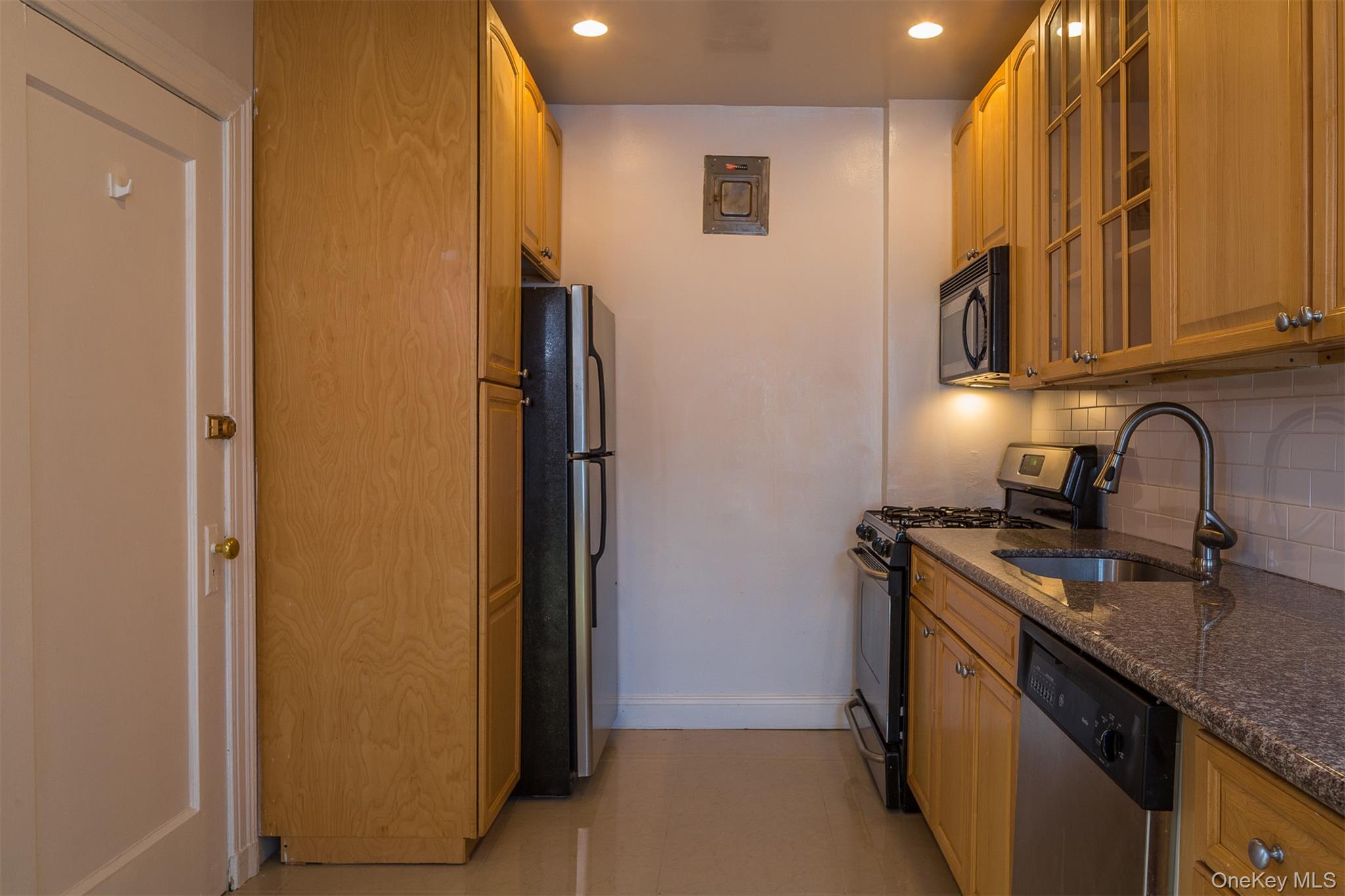 9 Alden Place, Unit G9 Bronxville, NY 10708 - Photo 8 of 11 a kitchen with stainless steel appliances granite countertop a sink and a refrigerator with wooden cabinets
