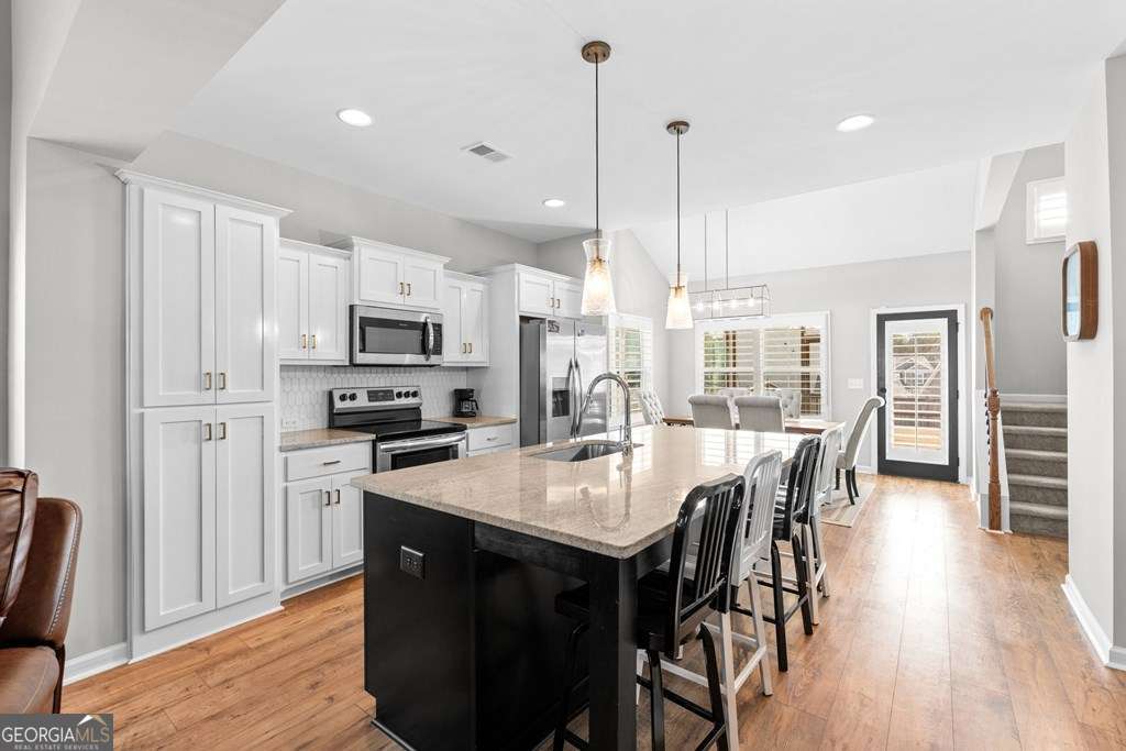 121 Cedar Pk Way Carrollton, GA 30117 - Photo 8 of 33 a kitchen with granite countertop a table chairs stainless steel appliances and wooden floor