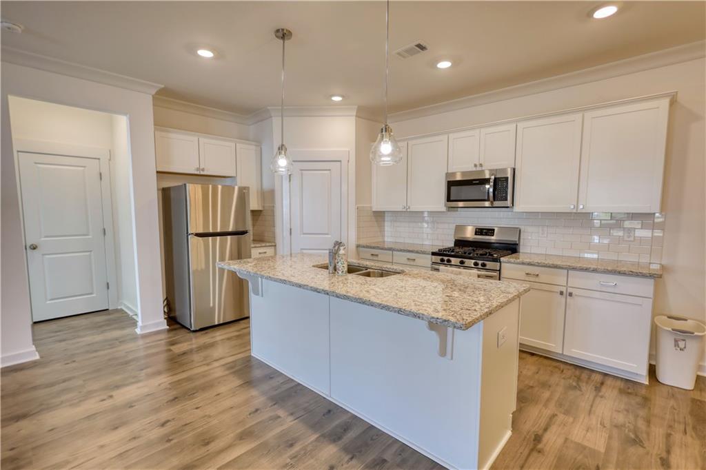 2929 Rambler Drive Loganville, GA 30052 - Photo 14 of 49 a kitchen with kitchen island granite countertop a refrigerator stove top oven and sink
