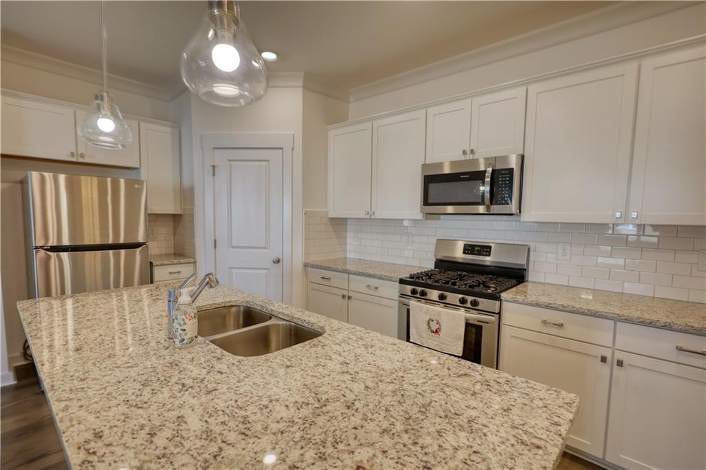 2929 Rambler Drive Loganville, GA 30052 - Photo 15 of 49 a kitchen with stainless steel appliances granite countertop a sink a stove a microwave a refrigerator a counter space and cabinets