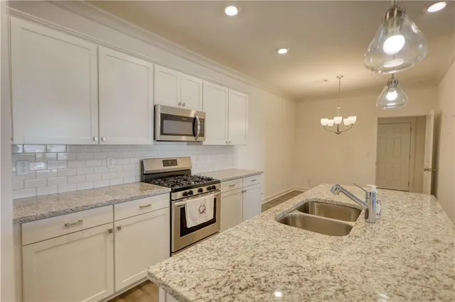 a kitchen with granite countertop a sink a stove and cabinets