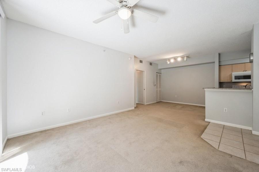 1170 Reserve Way, Unit 107 Naples, FL 34105 - Photo 15 of 41 Unfurnished living room featuring light carpet, rail lighting, and ceiling fan