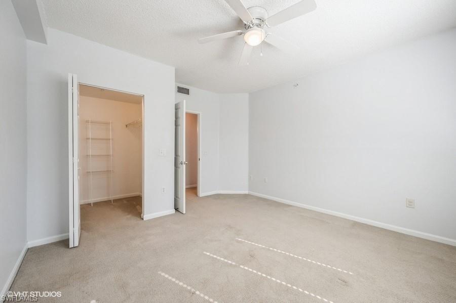 1170 Reserve Way, Unit 107 Naples, FL 34105 - Photo 19 of 41 Unfurnished bedroom with a spacious closet, light carpet, a textured ceiling, a closet, and ceiling fan