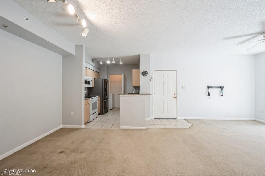1170 Reserve Way, Unit 107 Naples, FL 34105 - Photo 25 of 41 Unfurnished living room featuring light carpet, a textured ceiling, track lighting, and ceiling fan