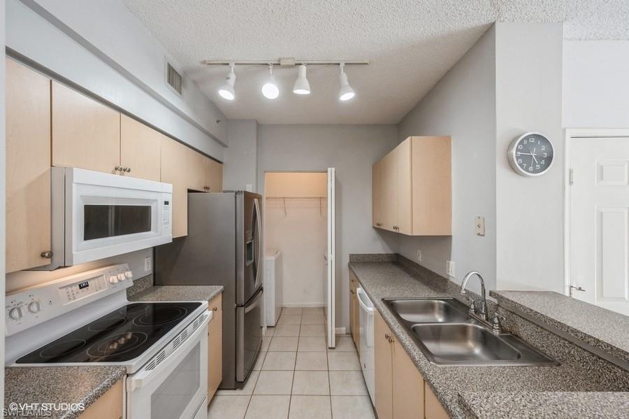 1170 Reserve Way, Unit 107 Naples, FL 34105 - Photo 8 of 41 Kitchen with sink, white appliances, light tile patterned floors, and a textured ceiling