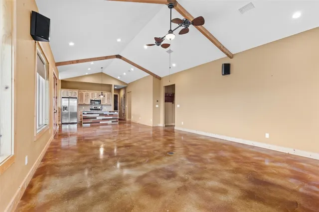 a view of a big room with wooden floor a chandelier fan and windows