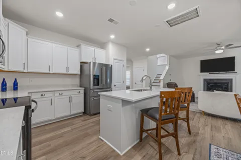 a kitchen with stainless steel appliances granite countertop a stove a sink a microwave a refrigerator and white cabinets