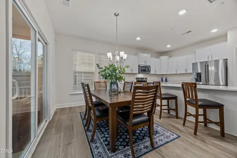 a kitchen with kitchen island a stove a refrigerator and a dining table with wooden floor