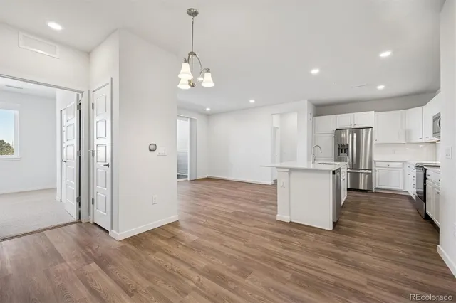 a view of kitchen and empty room with wooden floor