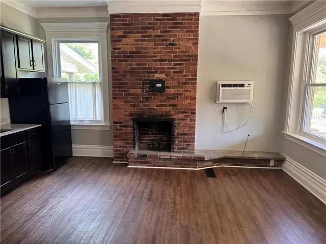 an empty room with wooden floor fireplace and windows