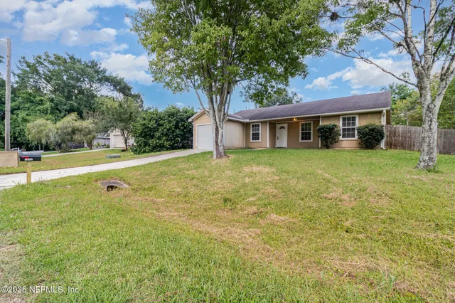 a view of a house with a backyard and a tree