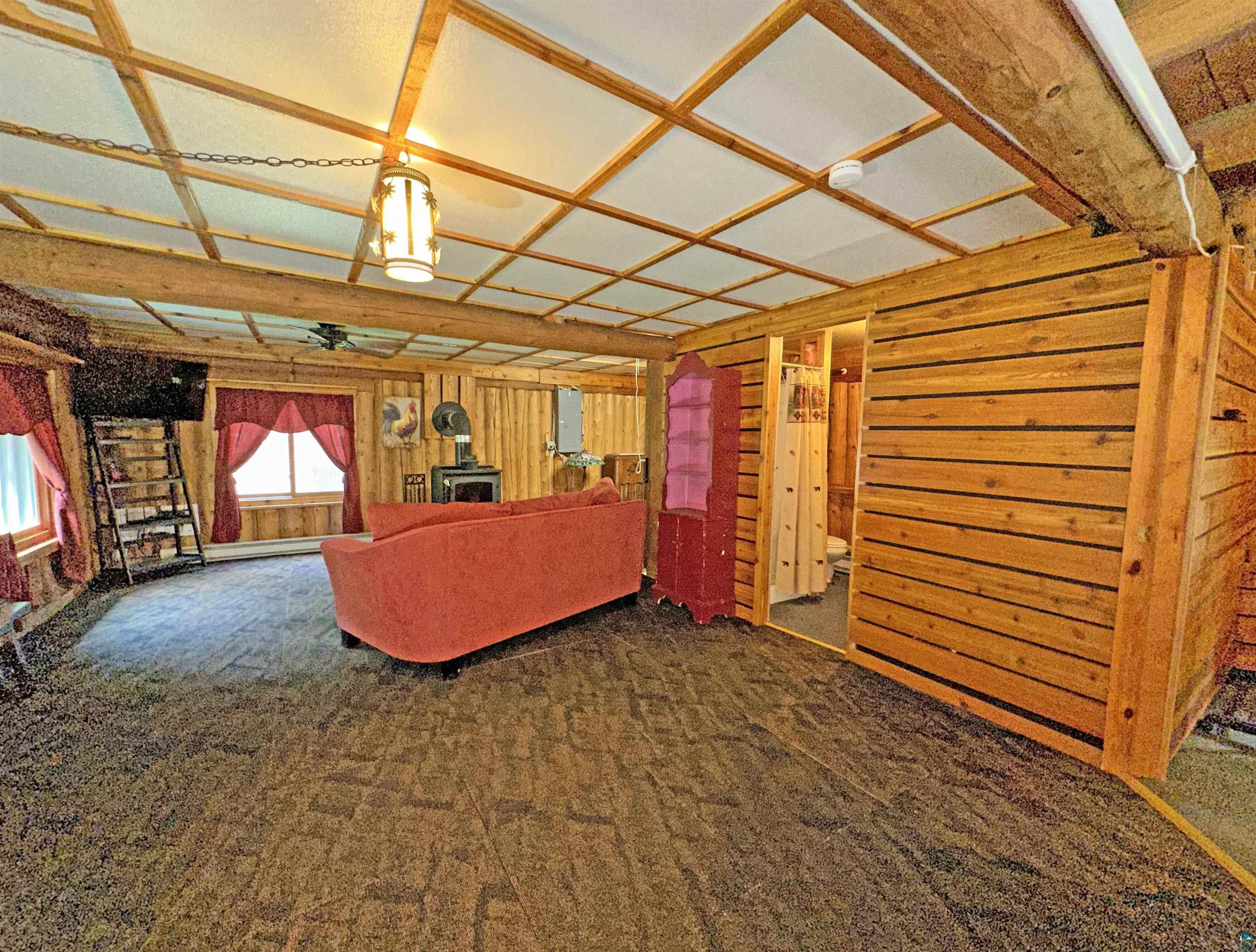 80590 Lenawee Road Herbster, WI 54844 - Photo 9 of 36 Basement featuring a wood stove, wood walls, carpet floors, and ceiling fan