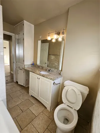 a bathroom with a granite countertop sink a toilet and a bathtub