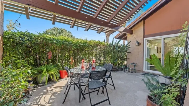 a patio with table and chairs and potted plants