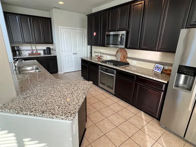 a kitchen with stainless steel appliances wooden cabinets a stove top oven a sink and dishwasher
