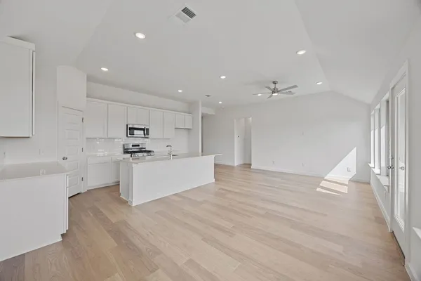 a view of kitchen with kitchen island white cabinets stainless steel appliances with wooden floor