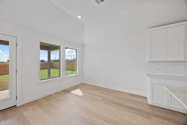 an empty room with wooden floor and windows