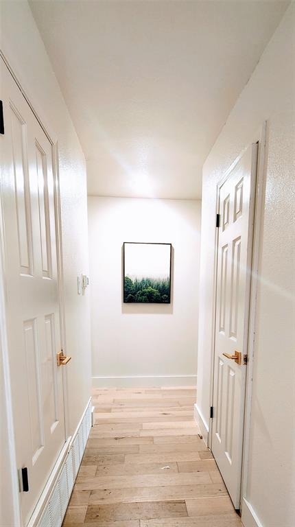 2908 Washington Street Commerce, TX 75428 - Photo 14 of 29 Bright hallway featuring wood-finish flooring, white paneled doors with gold-tone hardware, and white baseboards