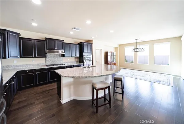 a kitchen with a stove a sink and a refrigerator with wooden floor