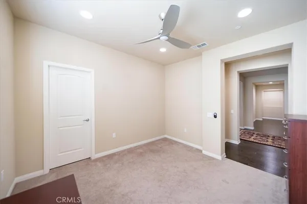 an empty room with windows and ceiling fan