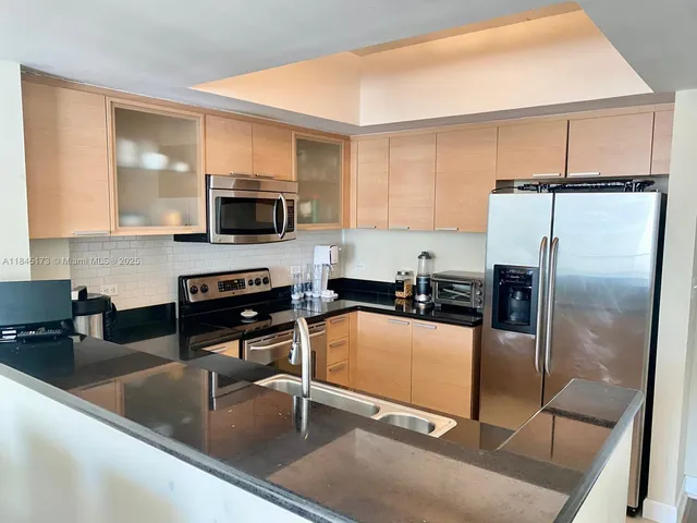 a kitchen with granite countertop a refrigerator a sink a stove and cabinets