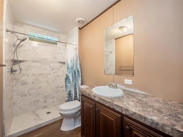 a bathroom with a granite countertop sink toilet and shower