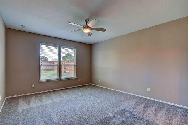 an empty room with a ceiling fan and window