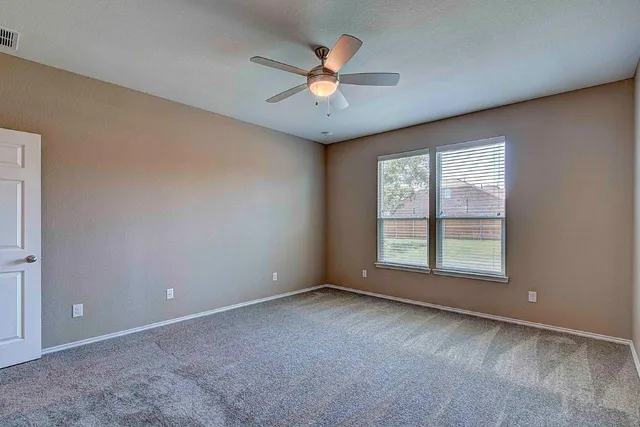 an empty room with windows and ceiling fan