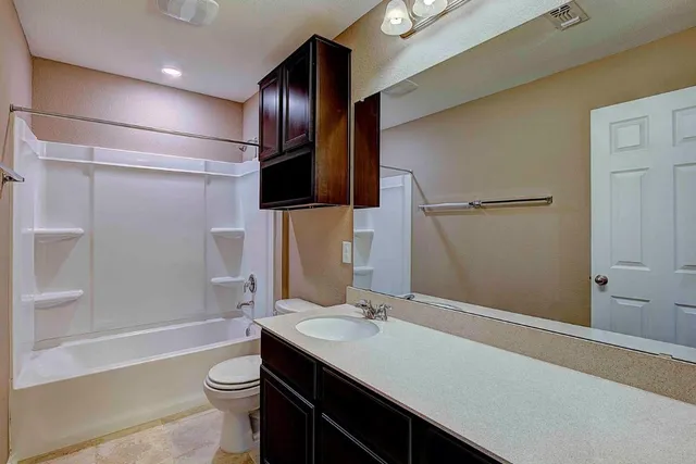 a bathroom with a sink a toilet a mirror and shower