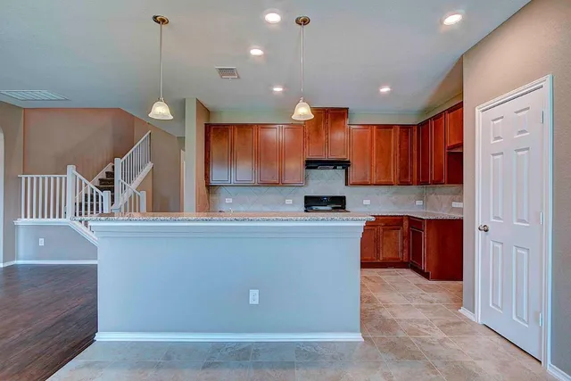 a large kitchen with stainless steel appliances kitchen island granite countertop a stove a sink and a refrigerator