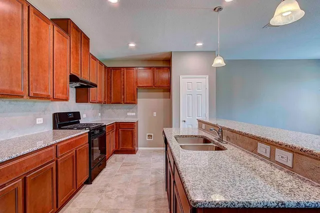 a kitchen with stainless steel appliances granite countertop wooden cabinets a stove a sink and a refrigerator