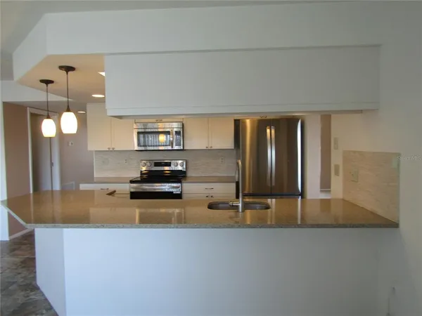 a kitchen with stainless steel appliances kitchen island granite countertop a refrigerator a stove top oven a sink and dishwasher