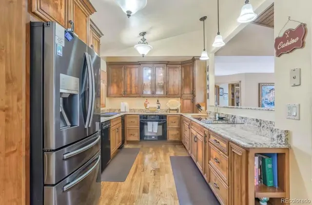 a kitchen with stainless steel appliances granite countertop a refrigerator a sink a stove and dishwasher