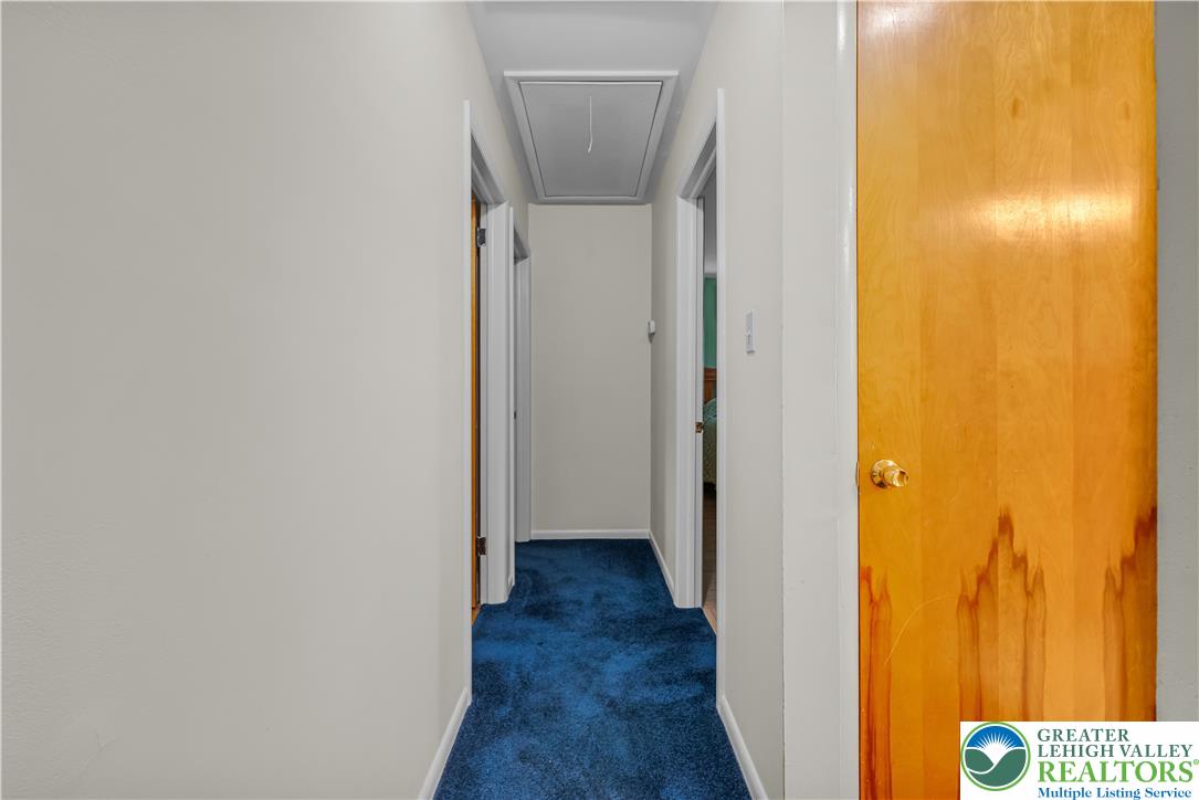 2750 Belaire Road Bethlehem, PA 18017 - Photo 22 of 56 Deep blue carpeting lines a straightforward hallway leading to multiple rooms and attic access.