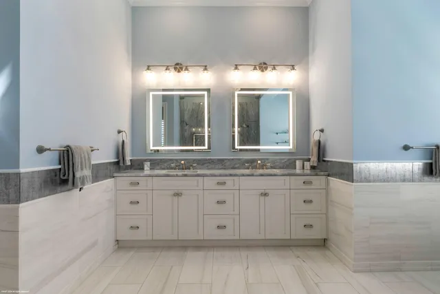 a bathroom with a granite countertop double vanity sink a mirror and a bathtub