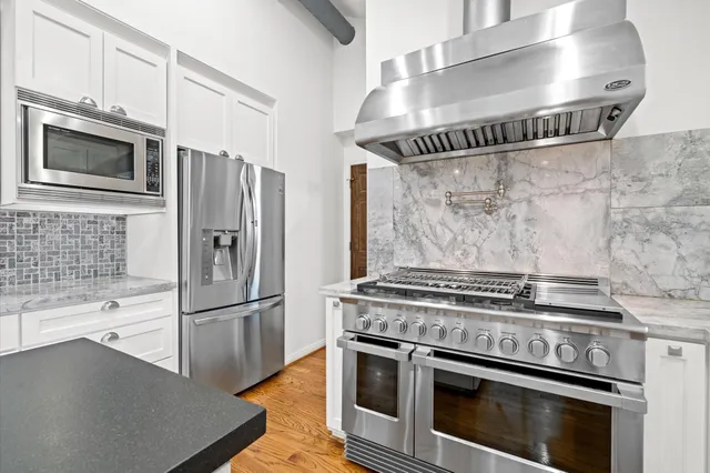a kitchen with granite countertop a stainless steel stove and refrigerator