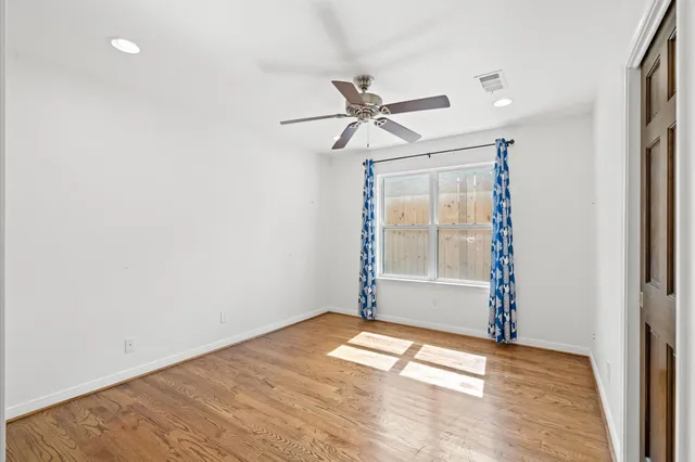 a view of empty room with window and ceiling fan