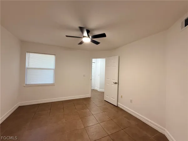 a view of an empty room with a ceiling fan and window