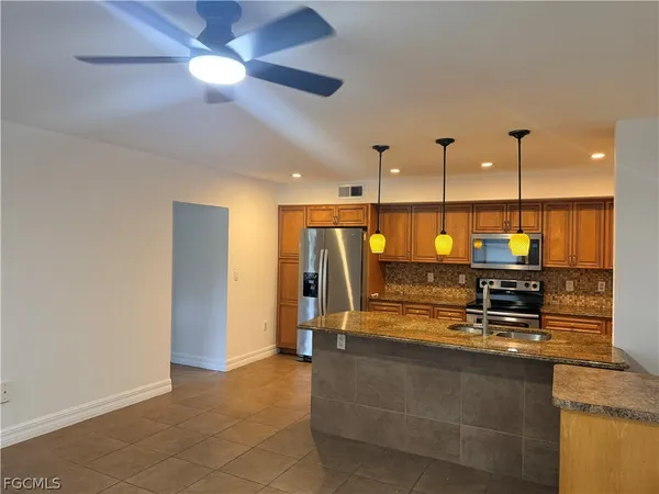 a kitchen with kitchen island a counter top space appliances and a ceiling fan