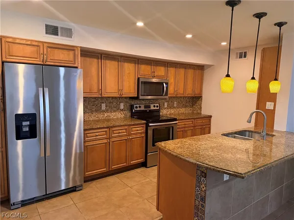 a kitchen with stainless steel appliances granite countertop a refrigerator a stove top oven a sink and dishwasher