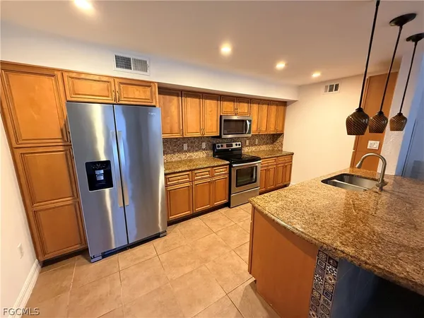 a kitchen with stainless steel appliances granite countertop a refrigerator stove and sink